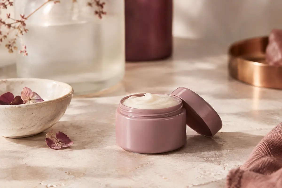 Après-shampooing Moroccanoil à l’huile d’argan posé sur pierre claire près d’une coupelle ivoire.