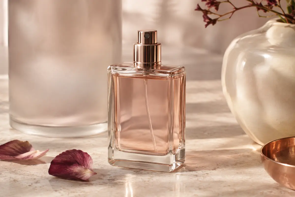 Flacon vaporisateur d’eau de parfum pour homme posé sur une pierre claire dans un décor ivoire