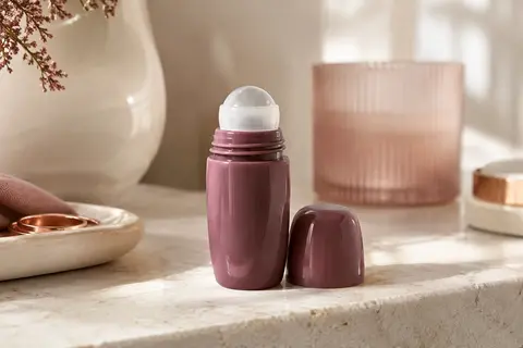 Déodorant Biotherm Deo Pure en flacon roll-on posé sur une pierre claire près d’une céramique ivoire.