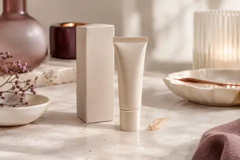 Tube de CC crème posé sur une pierre claire, près d’une coupelle en céramique ivoire.
