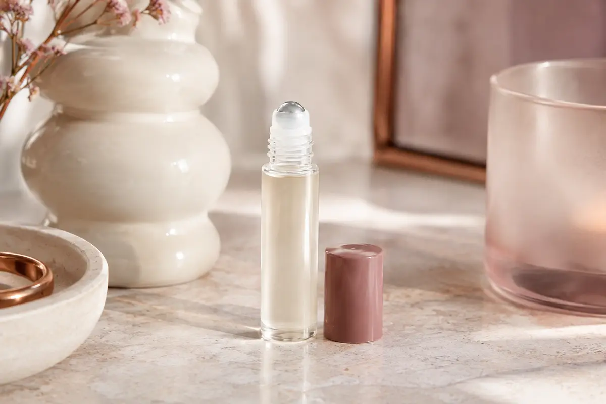 Flacon roll-on détranspirant posé sur une pierre claire, près d’un verre dépoli et d’une céramique ivoire.
