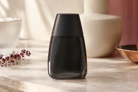 Flacon d’eau de toilette Drakkar Noir mis en scène sur une pierre claire avec du romarin