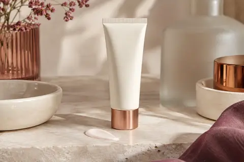 Lotion solaire visage Hawaiian Tropic SPF 30 présentée sur une pierre claire près d’une céramique ivoire.