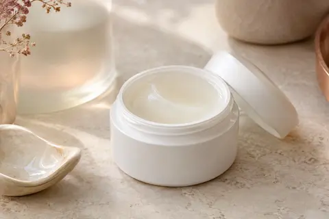 Pot blanc de baume nettoyant Heimish ouvert, avec sa texture baume sur une surface en pierre claire.