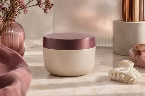 Masque capillaire Metal Detox posé sur une pierre claire, près d’une coupelle en céramique ivoire.