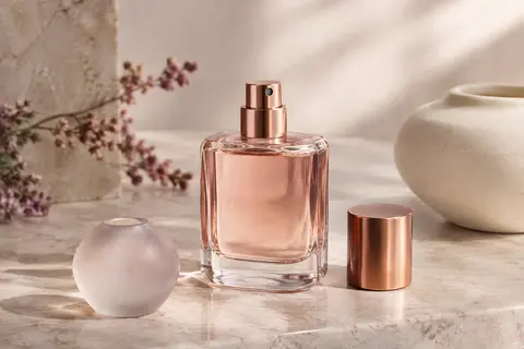 Flacon violet facetté de l’eau de parfum Mugler Alien posé sur une pierre claire.
