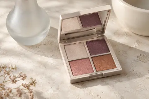 Palette de fards à paupières ouverte avec quatre poudres satinées, posée sur une surface claire.