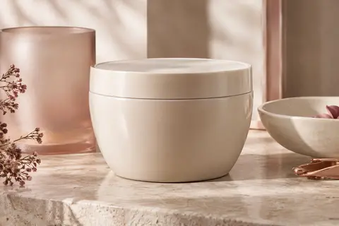 Masque capillaire nourrissant présenté sur une pierre claire avec une texture crémeuse et des accessoires ivoire.